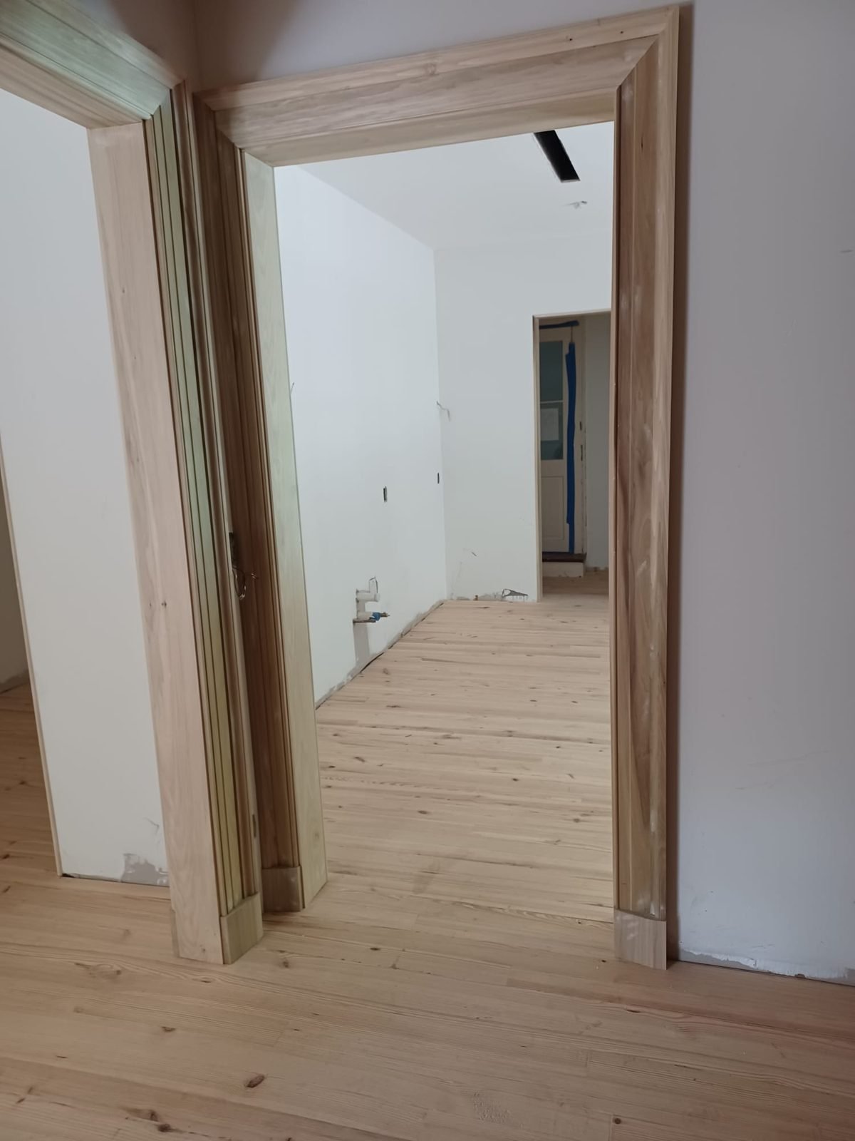 New pine flooring meeting fresh baseboards and wide door casing