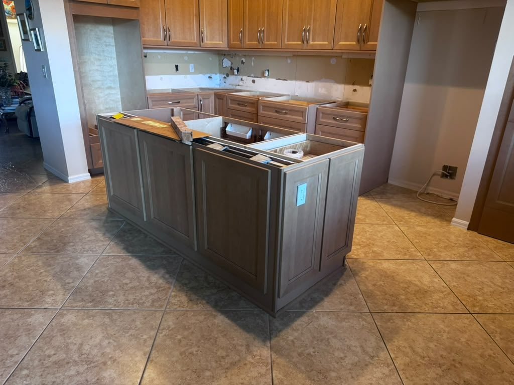 Kitchen island base cabinets being installed on a tile floor before the countertop