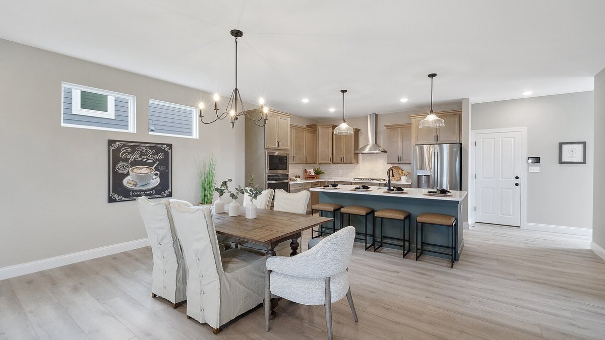Finished kitchen remodel with a blue island, pendant lights and an open dining area
