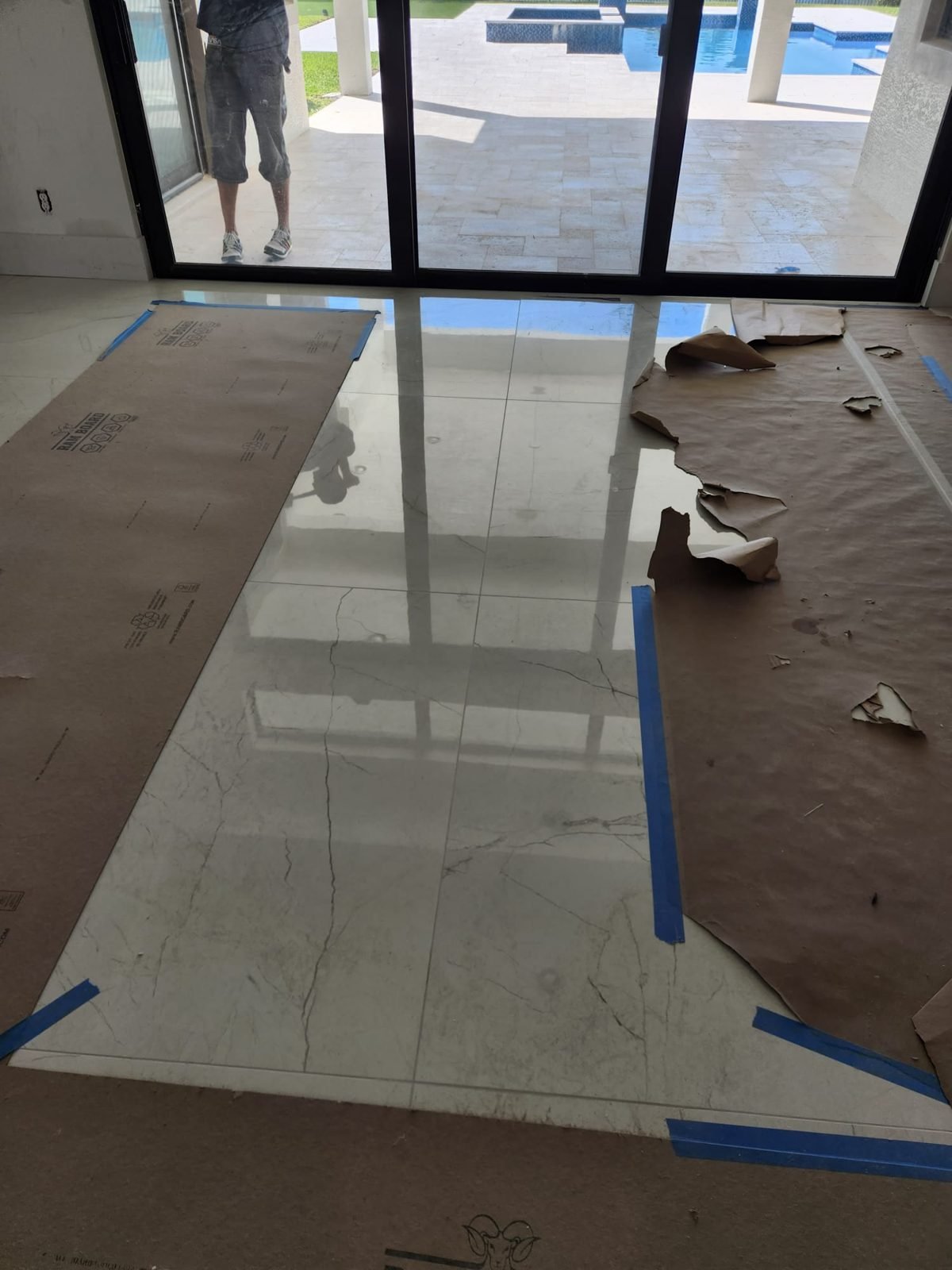 Marble-look porcelain tile floor installed by sliding doors facing the pool