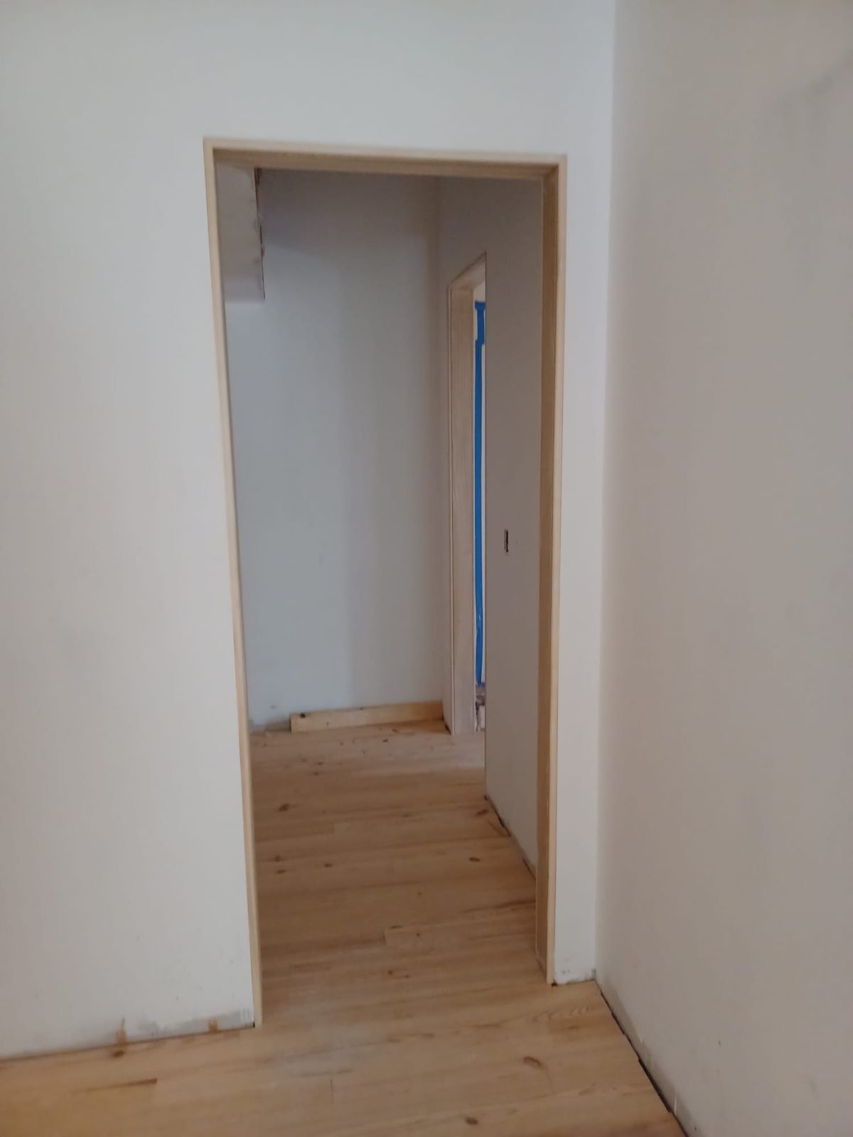 New pine floor running through a doorway with fresh wood casing