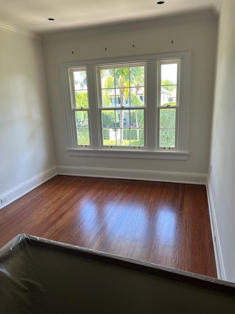 Refinished wood floor in a bright bedroom with a triple window