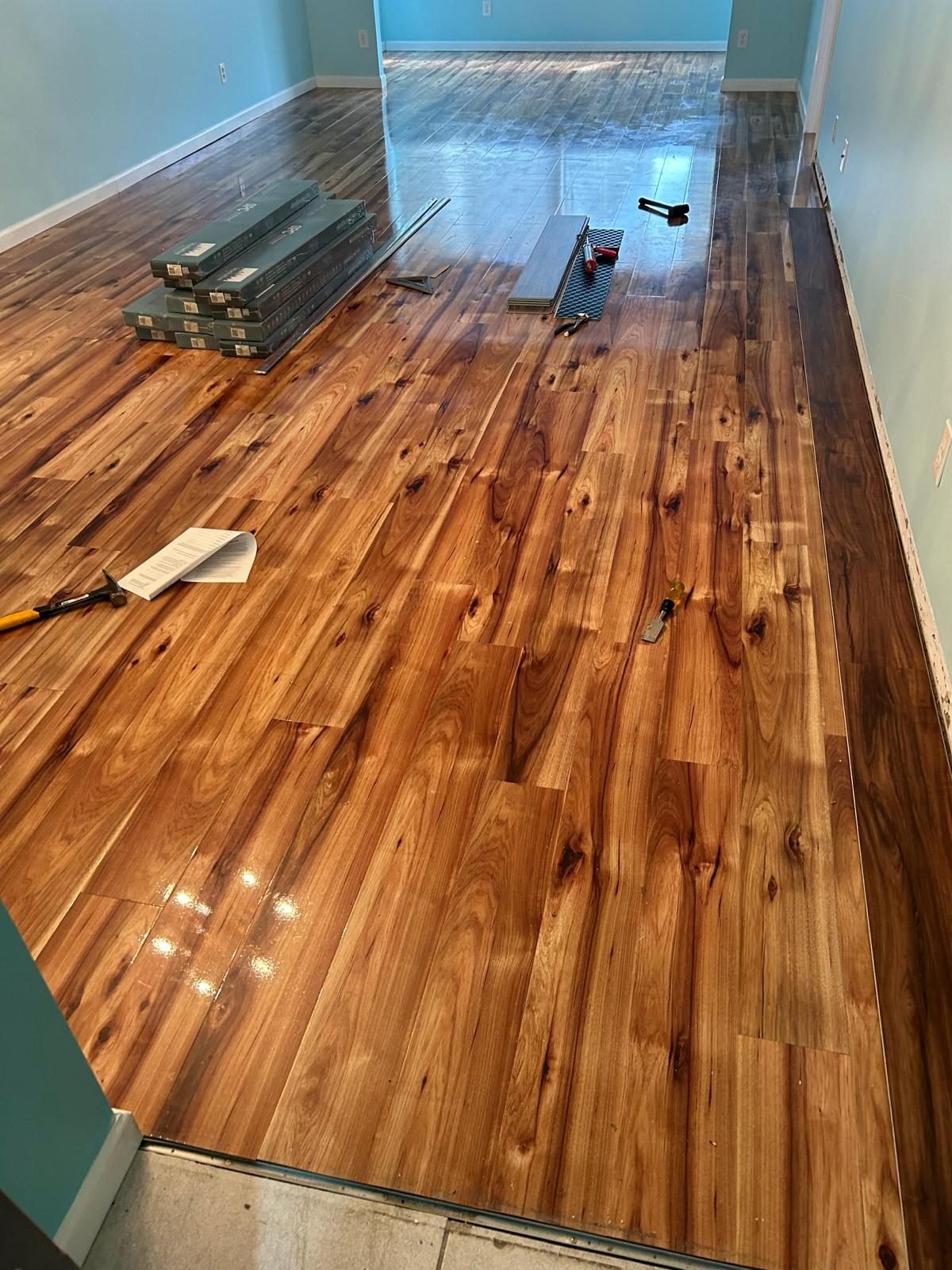 Solid wood plank floor being installed across a bedroom