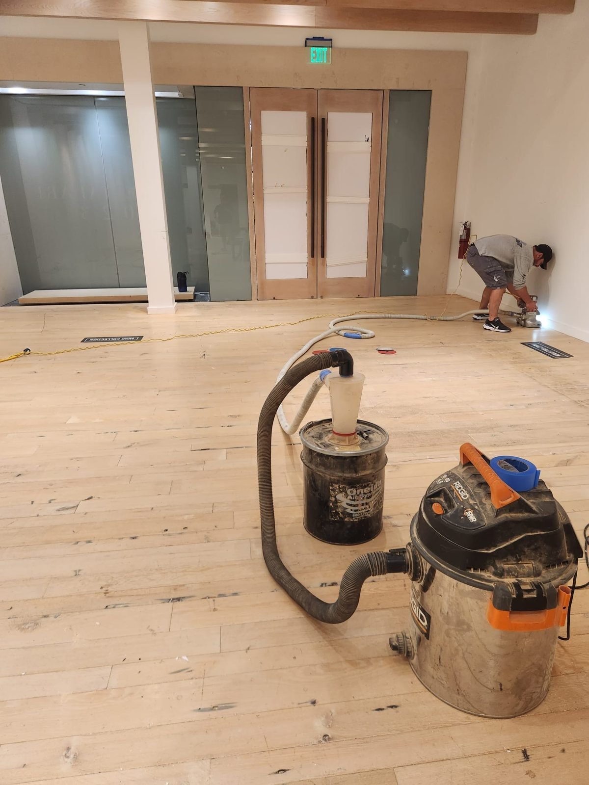 Wood floor being sanded for refinishing with dust extraction running